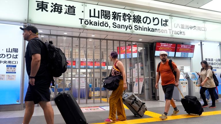 Travelers walk past the closed gate for Tokaido and Sanyo...