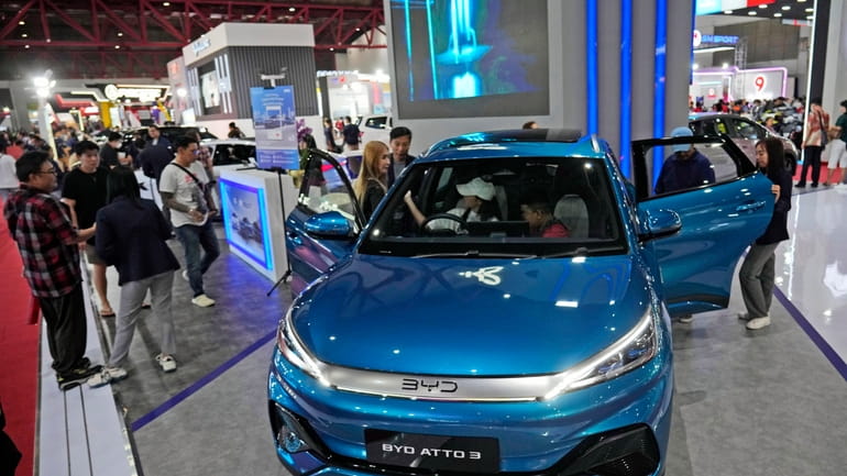 People inspect electric vehicles made by Chinese automaker BYD during...