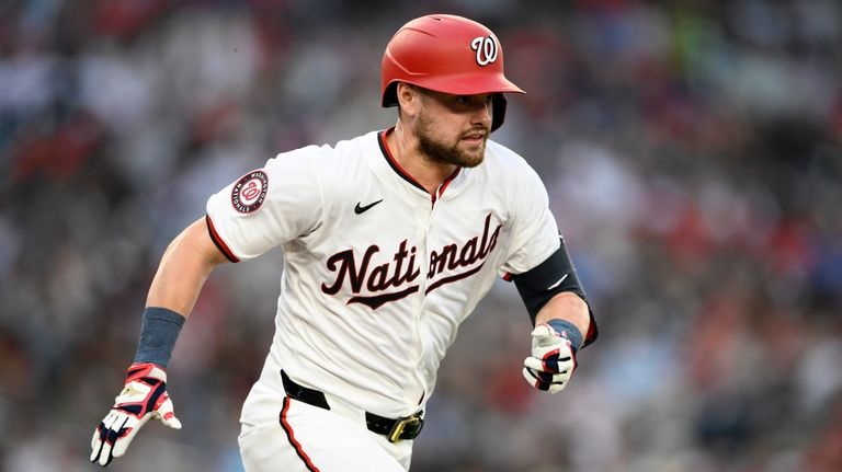 Washington Nationals' Lane Thomas runs to first on his ground...