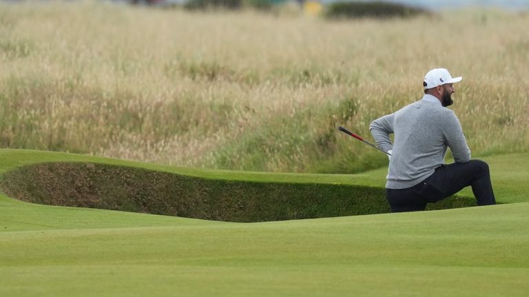 Jon Rahm of Spain stands in a fairway bunker on...