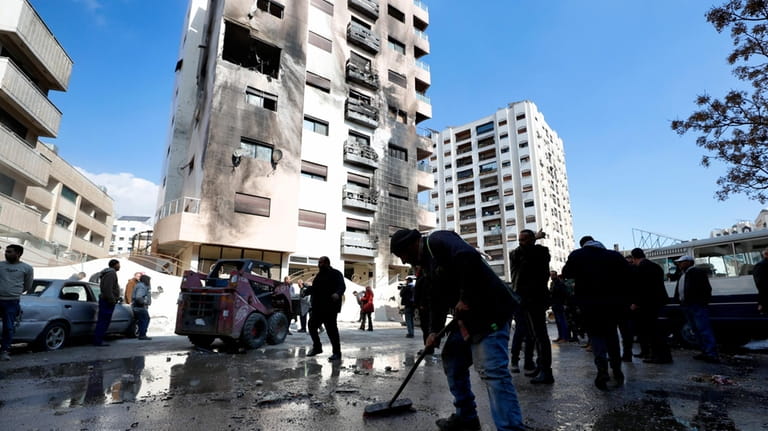 A man sweeps rubble near a residential building after a...