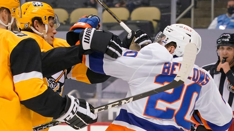 The Islanders' Kieffer Bellows and the Penguins' Sam Lafferty tangle in front...