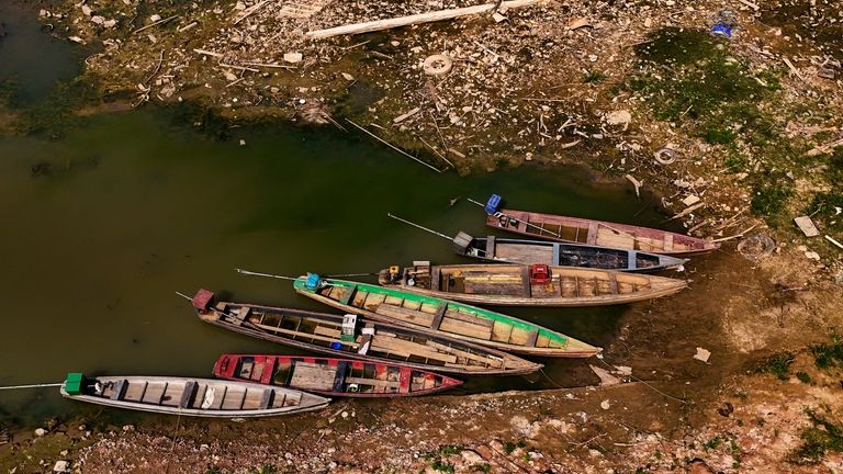 Boats sit on the bank of the Acre River, the...