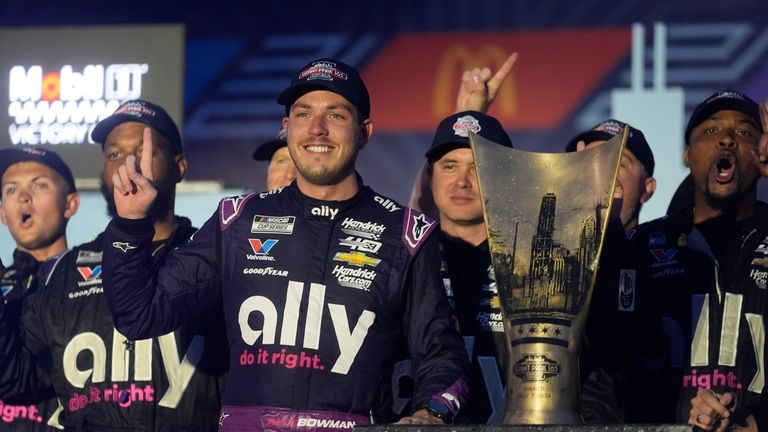 Alex Bowman stands with his team and his trophy after...