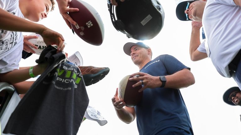 Seattle Seahawks head coach Mike Macdonald, center, signs autographs following...