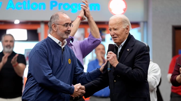 United Auto Workers President Shawn Fain, shakes hands with President...