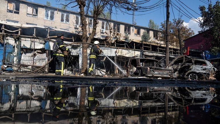 Rescue workers puts out a fire after a Russian rocket...