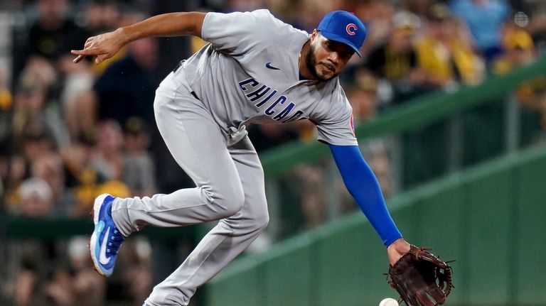 Chicago Cubs third baseman Jeimer Candelario reaches for a grounder...