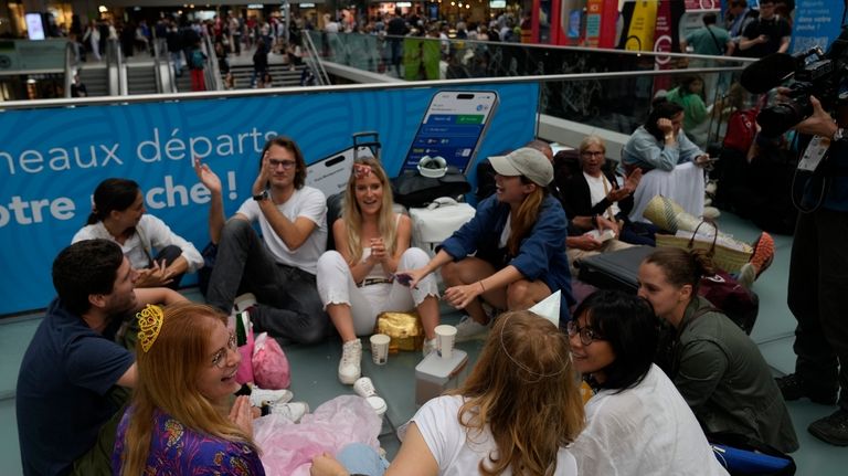 Travelers sit at the Gare de Montparnasse, at the 2024...