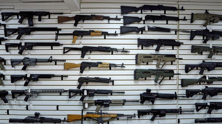 Semi-automatic rifles line a wall in a gun shop in...