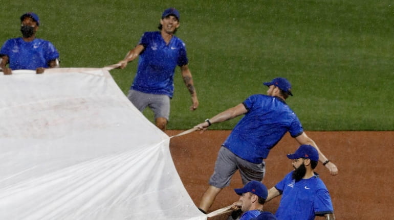 The grounds crew bring the tarp on the field during...