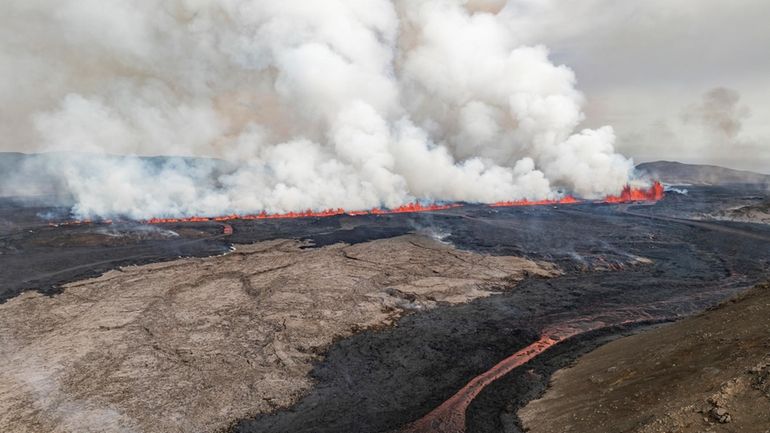 An eruptive fissure spews lava and smoke from a volcano...