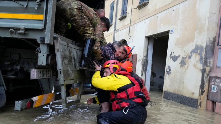 Firefighters rescue an elderly man in the flooded village of...