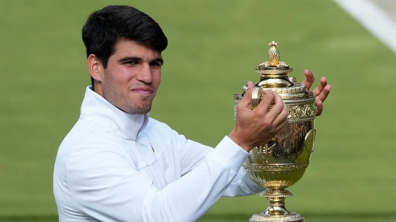 Carlos Alcaraz of Spain smiles as he holds up his...