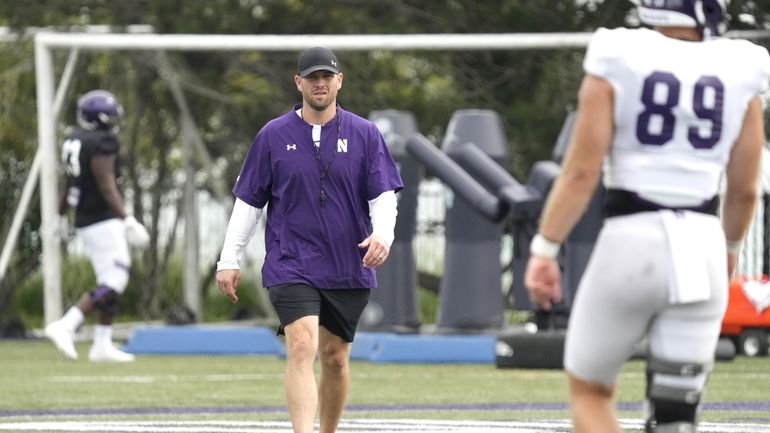 Northwestern interim head coach David Braun, center, walks on the...