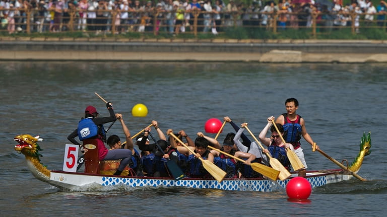 A team of dragon boat racers paddle their boat during...