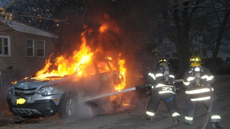 Firefighters douse a Chevrolet Captiva engulfed in flames in North...