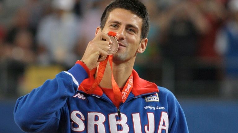 Serbia's Novak Djokovic displays his bronze medal won in singles...