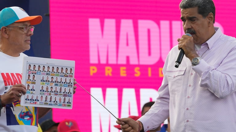 Venezuelan President Nicolas Maduro, right, points to a copy of...