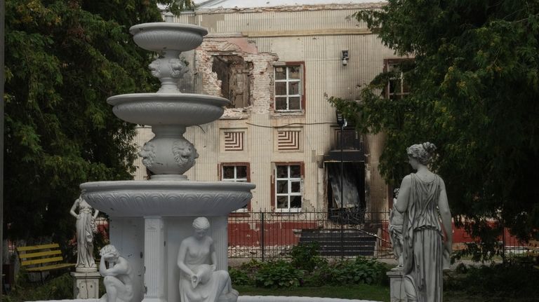 A fountain is seen against a background of a damaged...