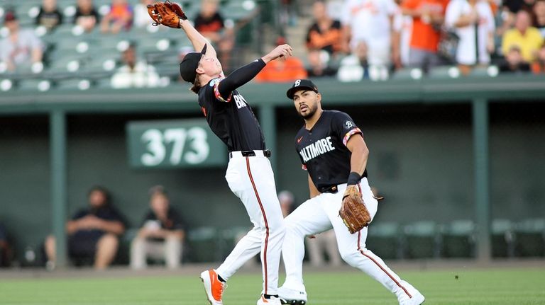 Baltimore Orioles second baseman Jackson Holliday, left, secures a popup...