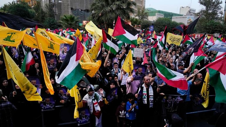 Iranian protesters wave Iranian, Palestinian and Lebanon's militant Hezbollah group...