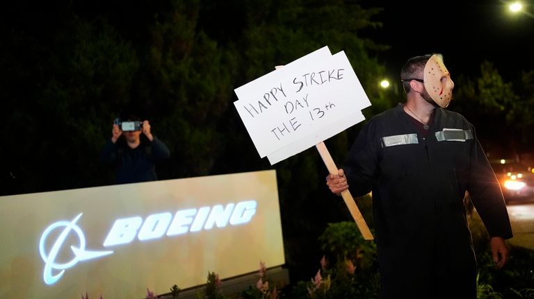 A Boeing worker wears a mask while holding a "happy...