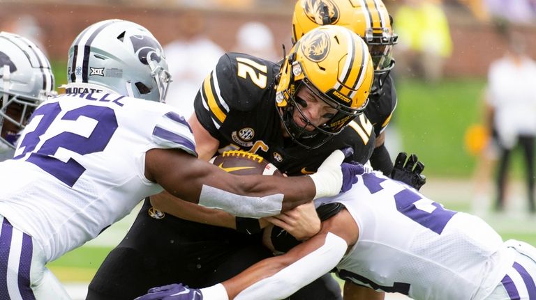 Missouri quarterback Brady Cook, center, is tackled by Kansas State...