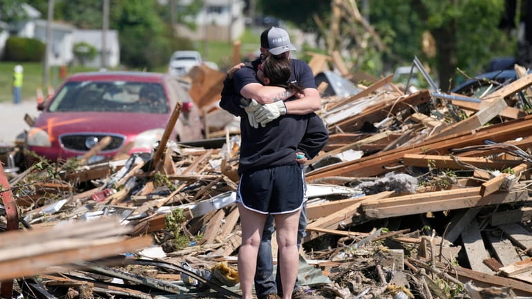 Local residents hug in front of their tornado damaged home,...