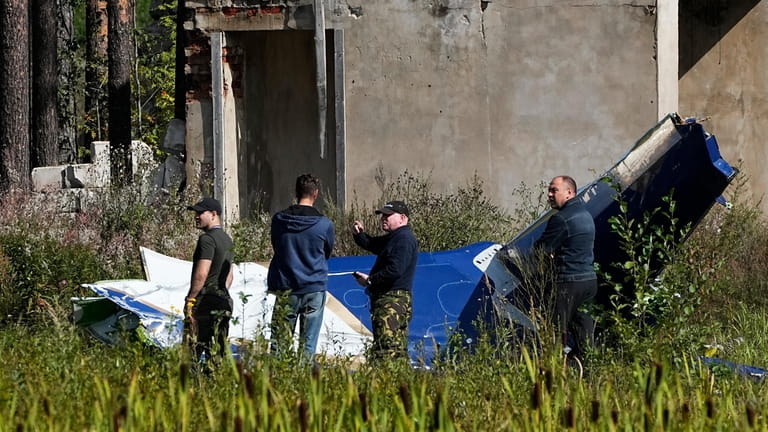 Russian investigators comb the scene of a jet crash near...
