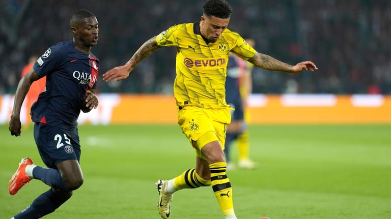 Dortmund's Jadon Sancho, right, challenges for the ball with PSG's...