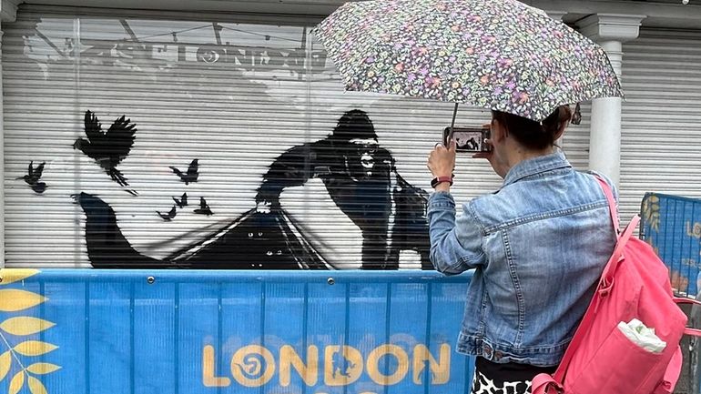 A woman photographs a mural by the elusive street artist...