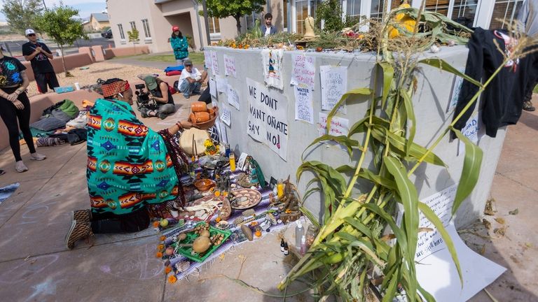 Activists place offerings at an empty pedestal where Rio Arriba...