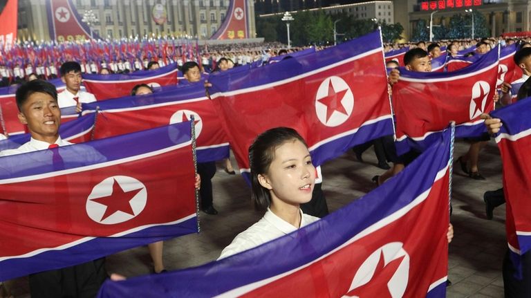 North Koreans march with their nationa flag as they celebrate...