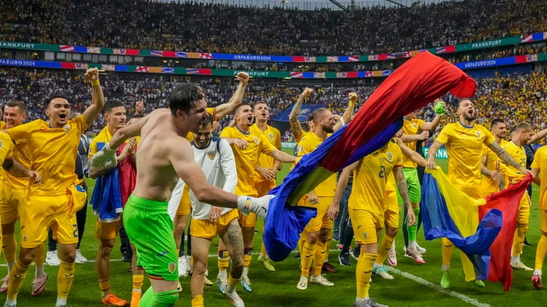 Romania's players celebrate at the end of the match during...