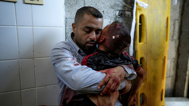 A Palestinian man holds the body of his child killed...
