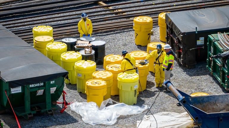 Workers with containers holding the drums exhumed in April at...