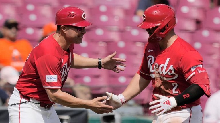 Cincinnati Reds' Ty France, right, celebrates with third base coach...