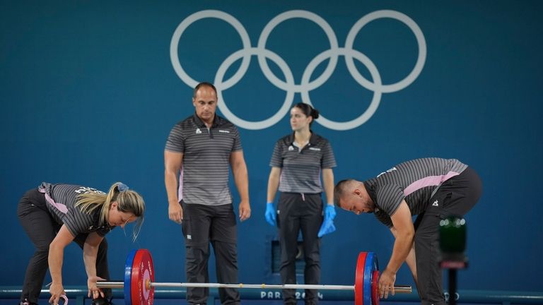 Loaders set the weight on the bar during the women's...