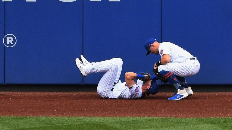 Mets leftfielder Jeff McNeil is tended to by center fielder...