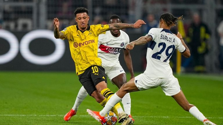 PSG's Bradley Barcola, right, and Dortmund's Jadon Sancho compete for...