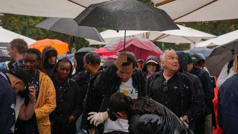 A spectator carries an umbrella receives a security check at...