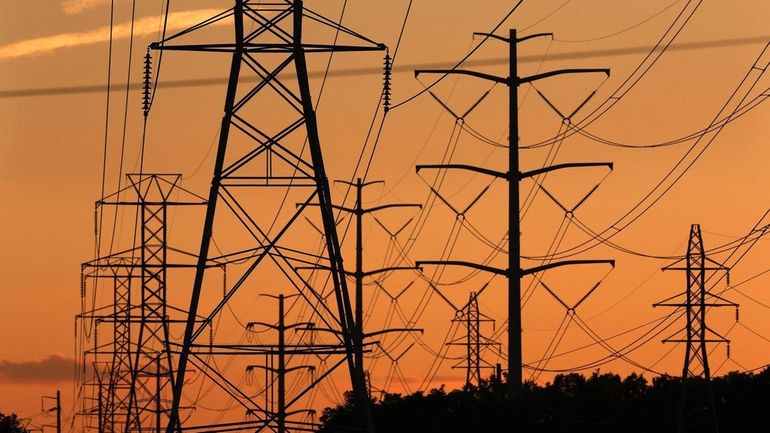 Transmission towers carry power lines through Suffolk County on Monday,...