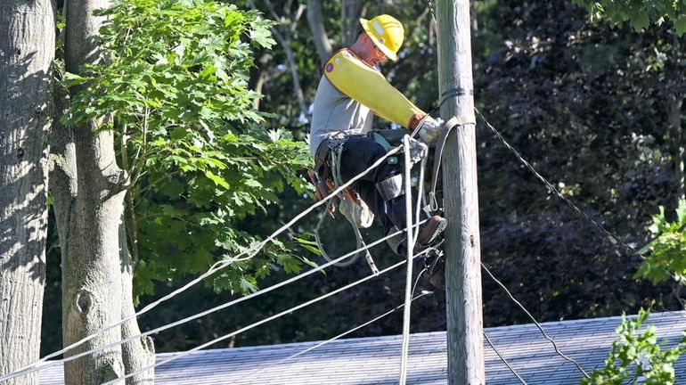 A PSEG workers labors to restore power in front of...