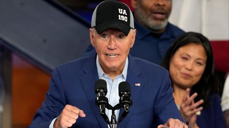 President Joe Biden wears a union hat as he speaks...