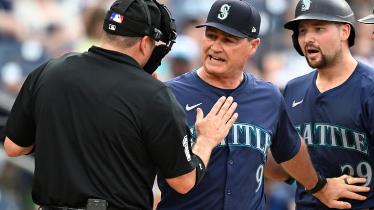 Home plate umpire Dan Bellino, left, talks with Seattle Mariners...