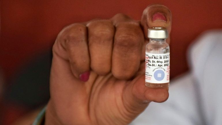 A health worker in Jammu, India, holds a vial of the...