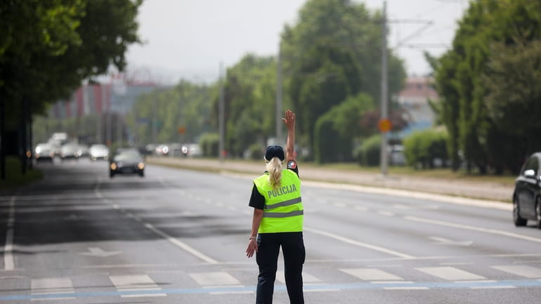 A police officer gestures towards cars as she tries to...