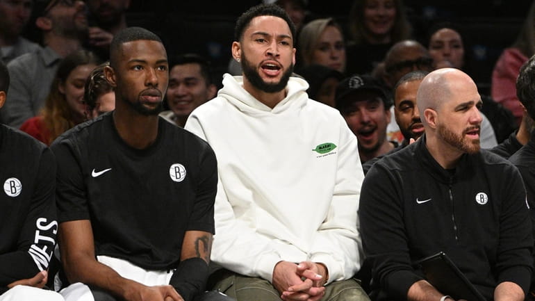 Nets guard Ben Simmons reacts on the bench in the...