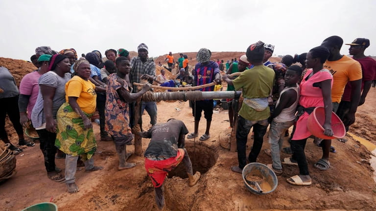 Miners work at an illegal tin mining site in Jos,...